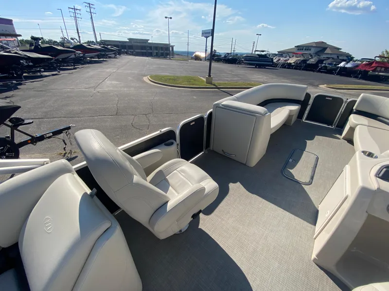 Slide: The Image of 2016 Manitou 25 Aurora pontoon boat interior with plush seating in a sunny dealership lot. - 20