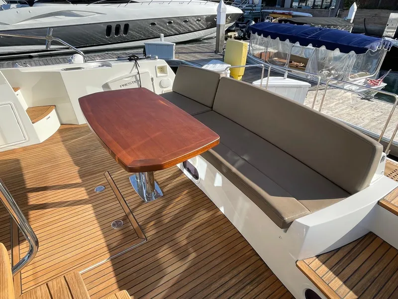 Slide: The Image of Prestige 500 Fly 2015 yacht with teak deck, cushioned seating, and wooden table. - 3