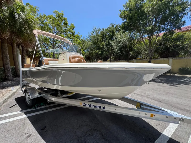 Slide: The Image of 2026 Pioneer 180 Islander boat on trailer, parked outdoors, surrounded by trees. - 1