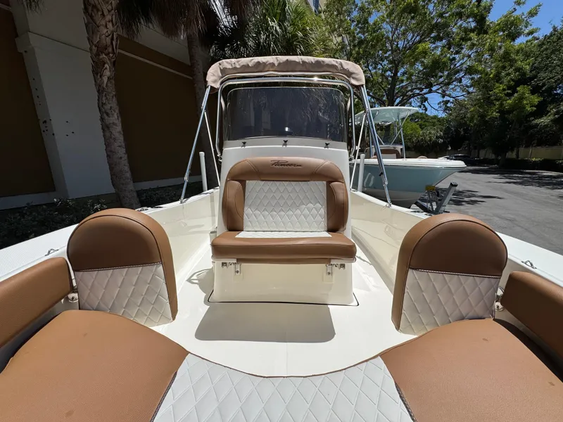 Slide: The Image of 2026 Pioneer 180 Islander boat interior with tan and white seating under a sunny sky. - 9
