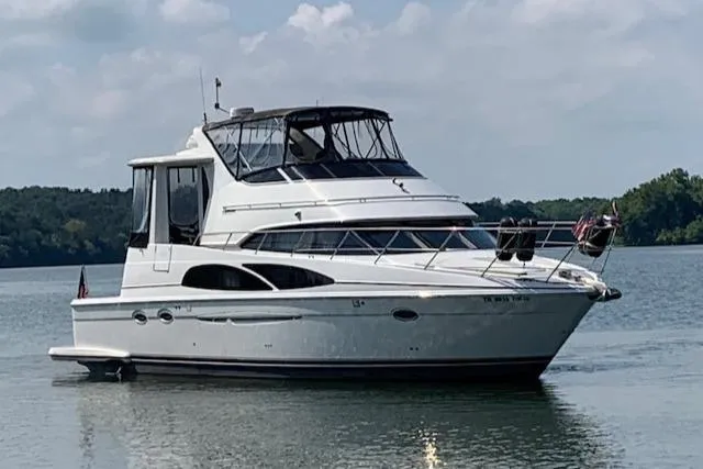 Slide: The Image of 2005 Carver 444 Cockpit Motor Yacht on calm water, under a partly cloudy sky. - 0