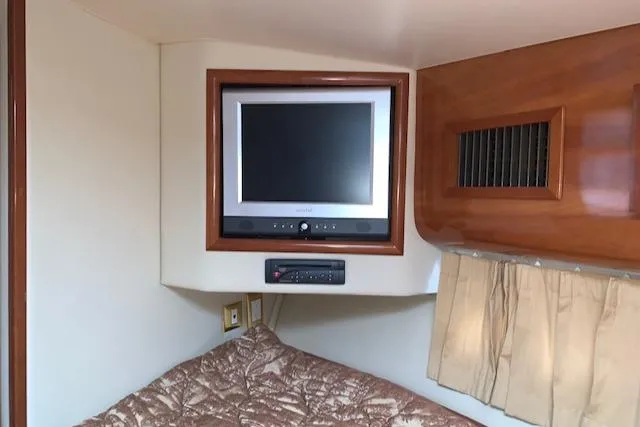 Slide: The Image of 2005 Carver 444 Cockpit Motor Yacht interior with TV and cozy bedding. - 23