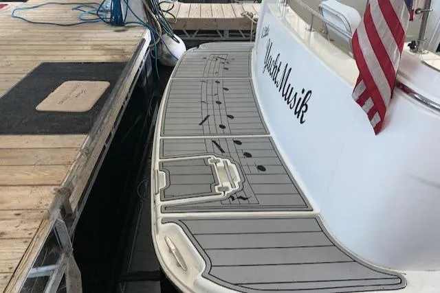Slide: The Image of 2005 Carver 444 Cockpit Motor Yacht docked, featuring a spacious swim platform and American flag. - 5