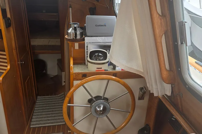 Slide: The Image of Interior of a 1987 Saturna 33 boat with wooden steering wheel and navigation equipment. - 13