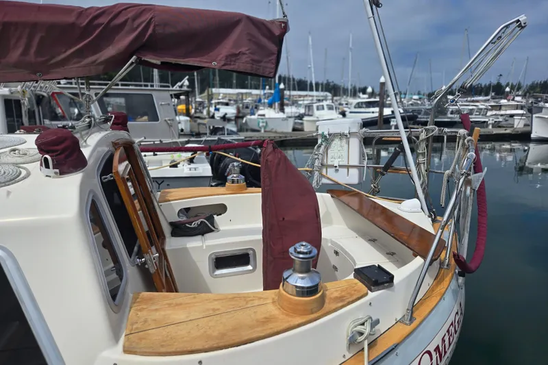 Slide: The Image of 1987 Saturna 33 sailboat docked in marina, featuring wooden accents and maroon covers. - 3