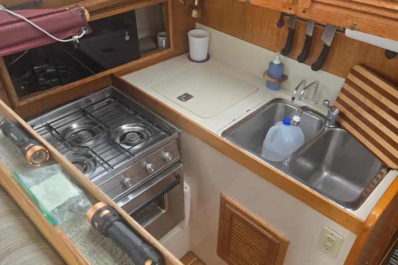 Slide: The Image of Compact kitchen in a 1987 Saturna 33 boat with stove, sink, and storage. - 8