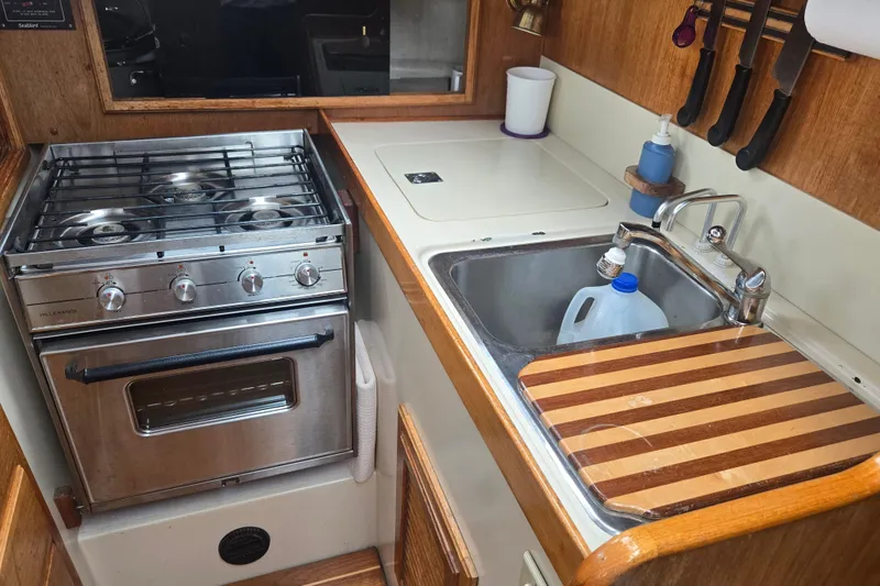 Slide: The Image of Compact kitchen in a 1987 Saturna 33 boat with stove, sink, and cutting board. - 9