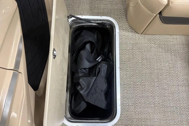 Slide: The Image of 2025 Barletta L25U boat seat with storage compartment open, showcasing beige upholstery. - 17