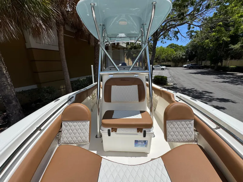 Slide: The Image of 2026 Pioneer 202 Sportfish boat interior with tan and white seating, under a sunny sky. - 13