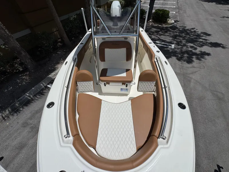 Slide: The Image of 2026 Pioneer 202 Sportfish boat interior with tan and white seating, parked outdoors. - 14