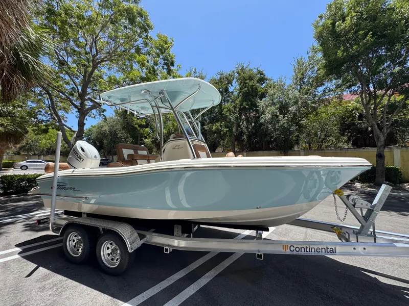 Slide: The Image of 2026 Pioneer 202 Sportfish boat on trailer, parked outdoors under sunny skies. - 2