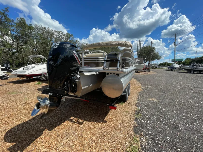 Slide: The Image of 2023 Bass Tracker Sportfish 24 DLX pontoon boat with Mercury outboard motor, parked outdoors. - 11