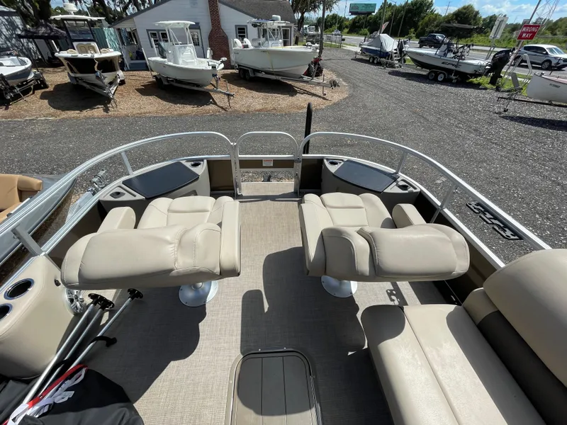 Slide: The Image of 2023 Bass Tracker Sportfish 24 DLX pontoon boat with beige seating, docked at a marina. - 3