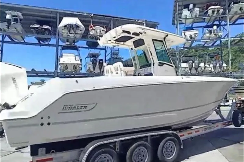 Slide: The Image of 2024 Boston Whaler 280 Outrage on trailer, surrounded by stacked boats in marina. - 1