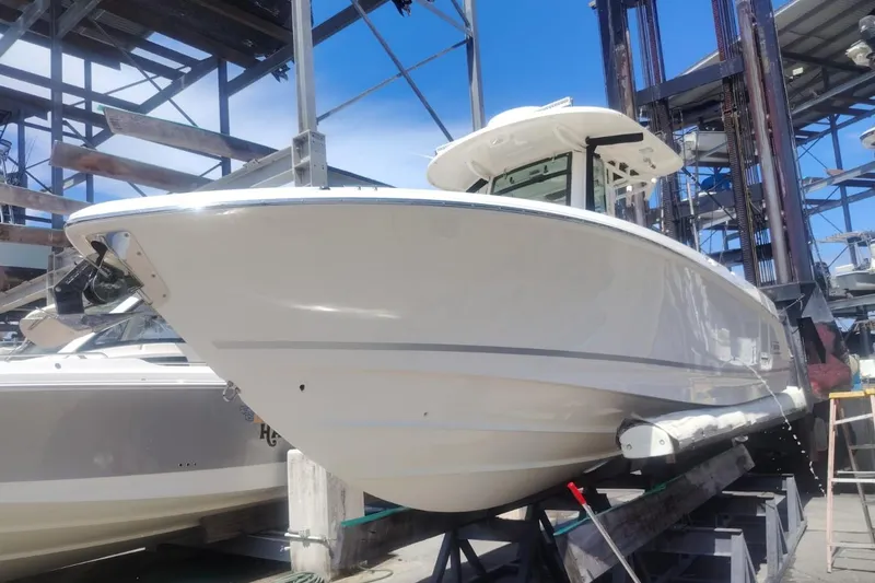 Slide: The Image of 2024 Boston Whaler 280 Outrage boat in dry dock, showcasing sleek design and sturdy build. - 5
