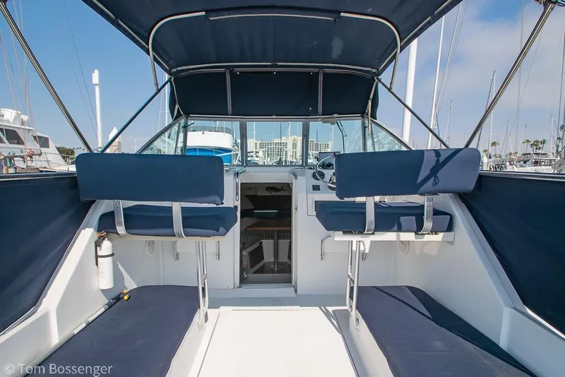 Slide: The Image of 1999 Mainship Pilot 30 boat interior with blue seating and canopy in marina. - 10