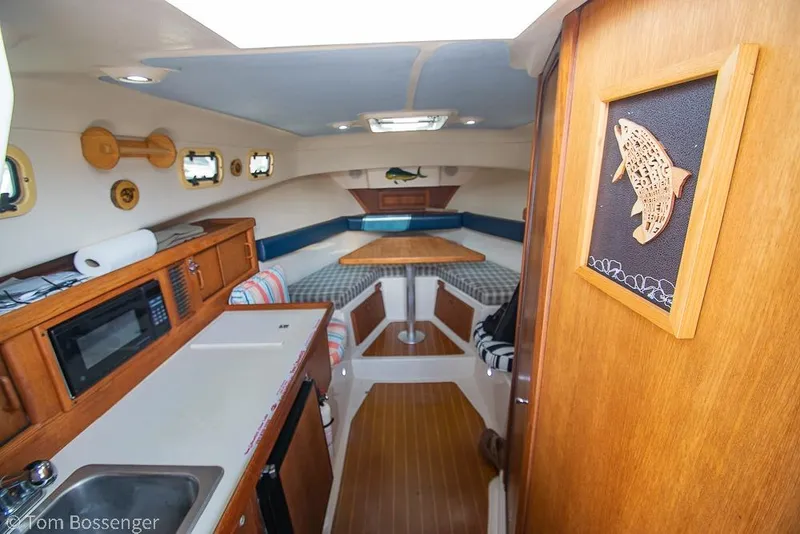 Slide: The Image of 1999 Mainship Pilot 30 interior with kitchenette, seating, and nautical decor. - 11