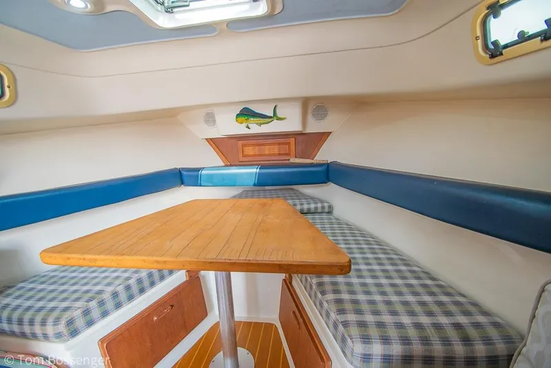 Slide: The Image of 1999 Mainship Pilot 30 cabin interior with wooden table and plaid seating. - 13