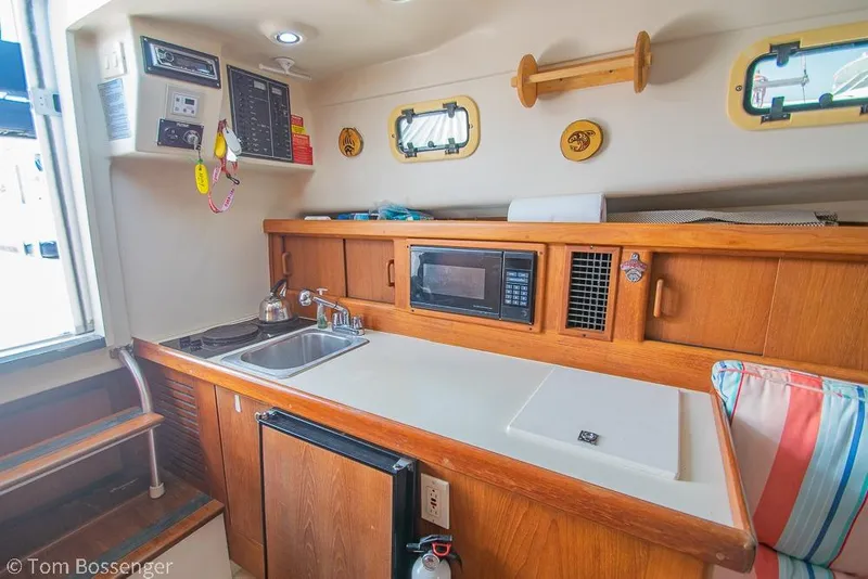 Slide: The Image of 1999 Mainship Pilot 30 galley with sink, microwave, and wooden cabinetry. - 14