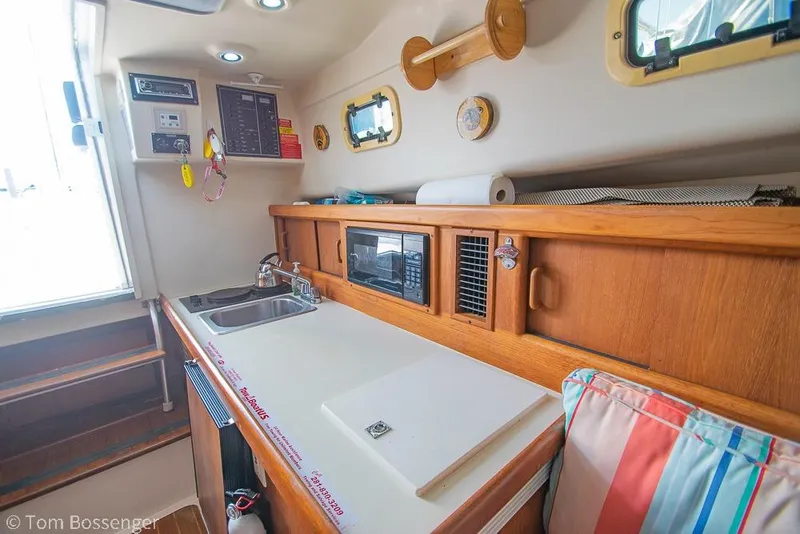 Slide: The Image of 1999 Mainship Pilot 30 interior kitchen with sink, microwave, and wooden cabinetry. - 15