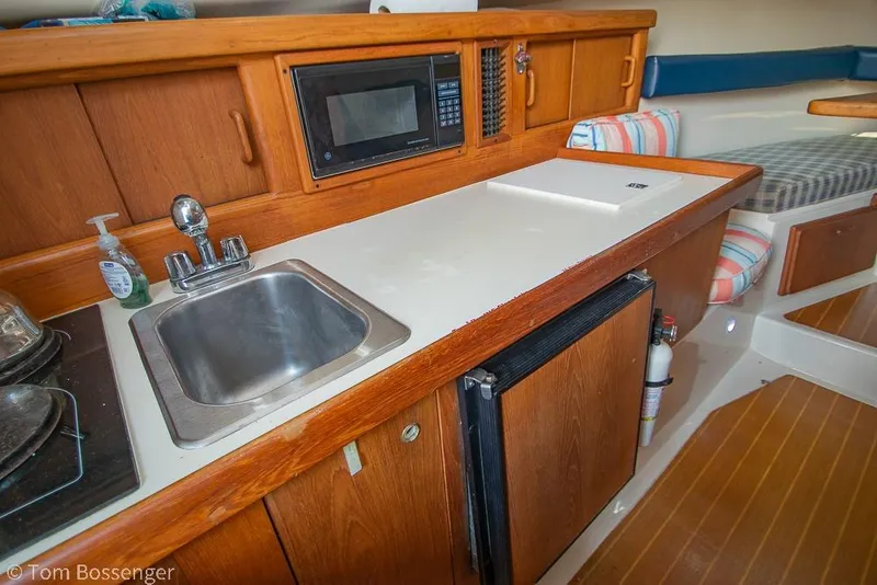 Slide: The Image of 1999 Mainship Pilot 30 interior with kitchenette, sink, microwave, and seating area. - 17