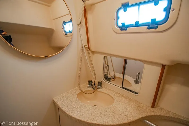 Slide: The Image of 1999 Mainship Pilot 30 boat bathroom with sink, mirror, and porthole window. - 23