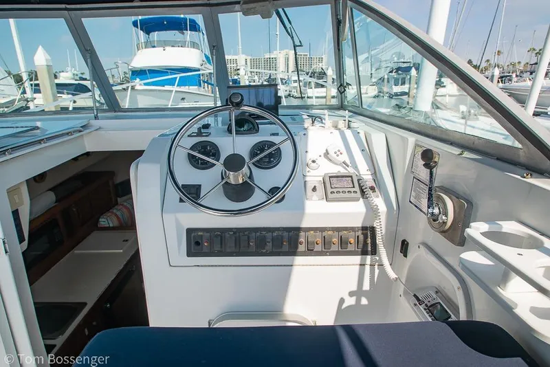 Slide: The Image of 1999 Mainship Pilot 30 helm with steering wheel, gauges, and marina view. - 24