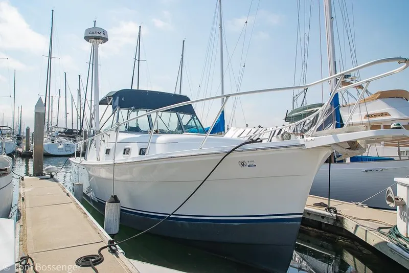 Slide: The Image of 1999 Mainship Pilot 30 docked at marina, featuring sleek design and blue canopy. - 3
