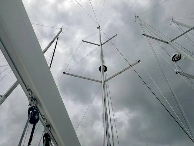 Slide: The Image of Jeanneau Sun Odyssey 410 sailboat masts against cloudy sky, 2024 model. - 13