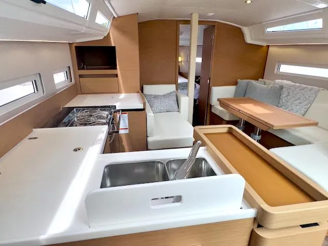 Slide: The Image of 2024 Jeanneau Sun Odyssey 410 interior with modern kitchen and cozy seating area. - 16