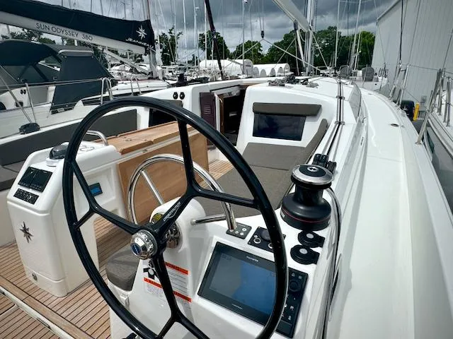 Slide: The Image of 2024 Jeanneau Sun Odyssey 410 sailboat cockpit with steering wheel and navigation equipment. - 2