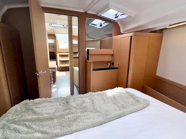 Slide: The Image of 2024 Jeanneau Sun Odyssey 410 interior cabin with modern wood finish and cozy bedding. - 21