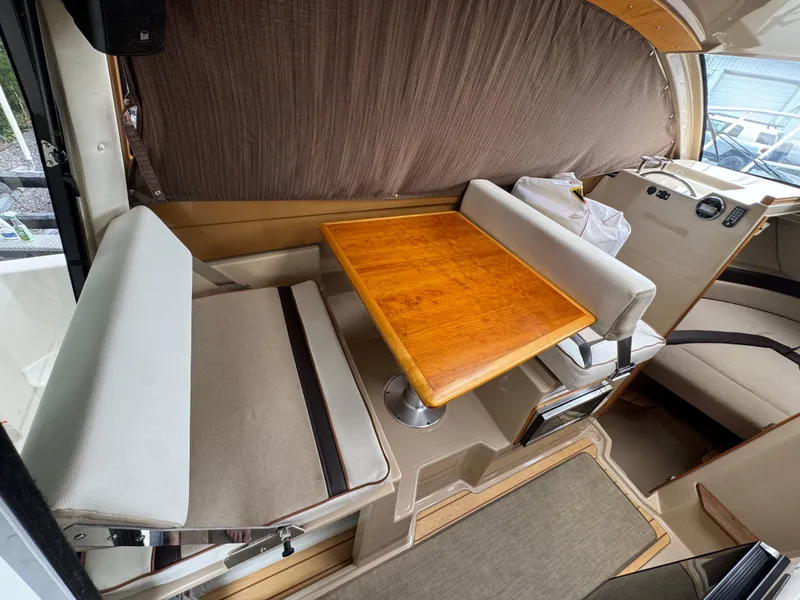 Slide: The Image of Interior of a 2016 Cutwater C-24 boat with a wooden table and cushioned seating. - 14