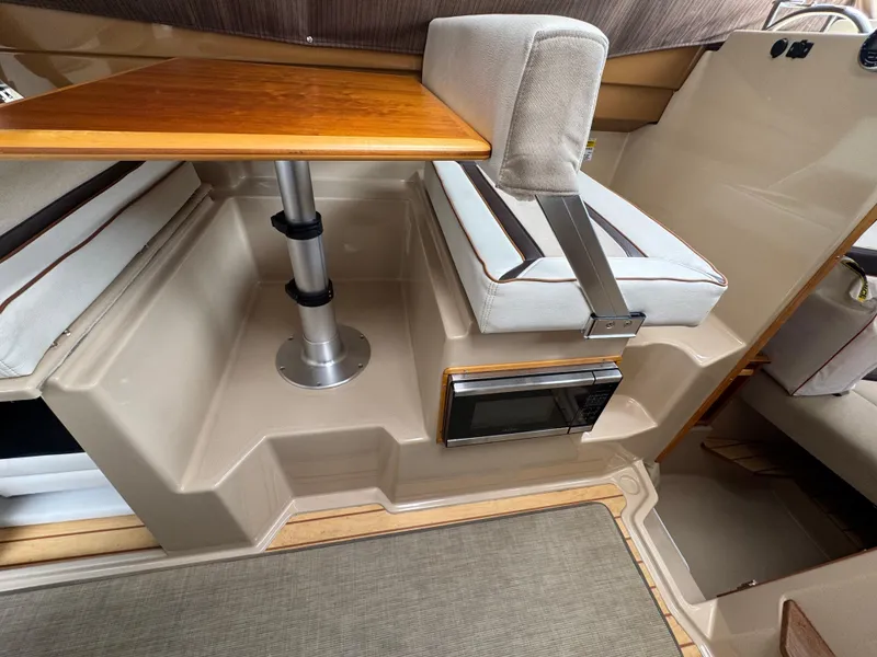 Slide: The Image of Interior of a 2016 Cutwater C-24 boat featuring a wooden table and cushioned seating. - 17