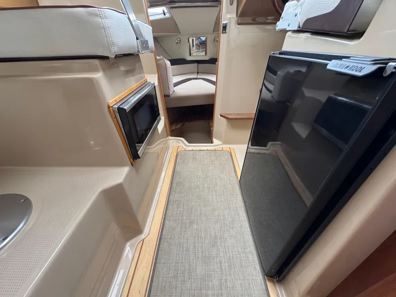 Slide: The Image of Interior of a 2016 Cutwater C-24 boat, featuring seating and a compact kitchen area. - 18