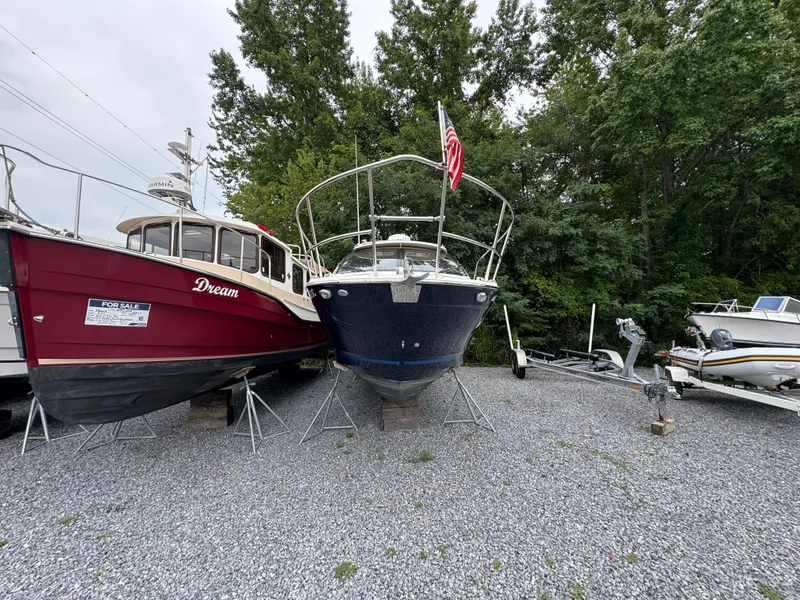 Slide: The Image of 2016 Cutwater C-24 boat on gravel lot, surrounded by trees and other boats. - 5