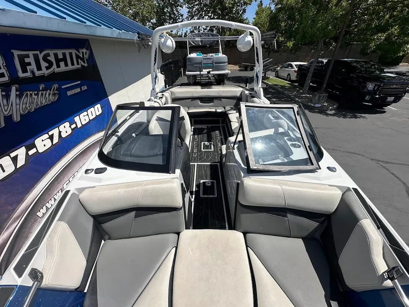 Slide: The Image of 2021 Centurion Fi23 boat interior with open seating, parked near a marine shop. - 26