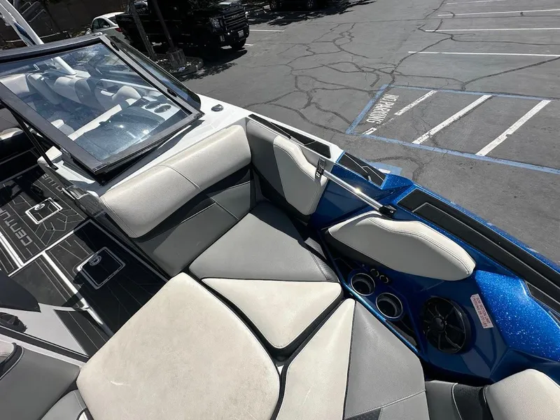 Slide: The Image of 2021 Centurion Fi23 boat interior with gray seating and blue accents in a parking lot. - 28
