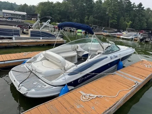 The Image of 2008 Crownline 240 EX boat docked on a lake with surrounding trees and other boats. - 0