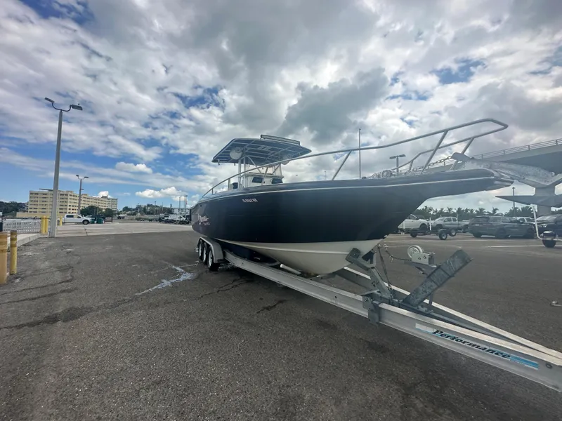 Slide: The Image of 2000 Stamas 290 Tarpon boat on a trailer in a parking lot under a cloudy sky. - 42