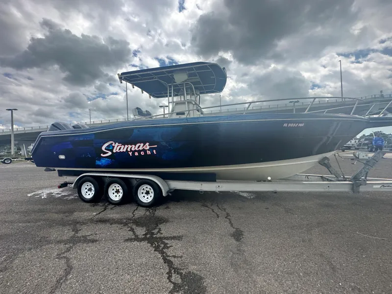 Slide: The Image of 2000 Stamas 290 Tarpon boat on a trailer under a cloudy sky. - 43