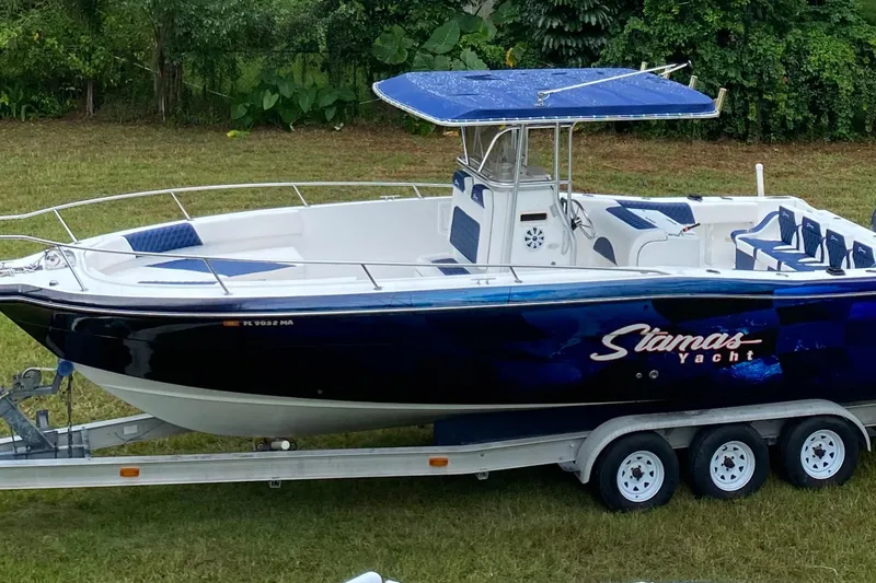 Slide: The Image of 2000 Stamas 290 Tarpon boat on a triple-axle trailer, parked on grass. - 48