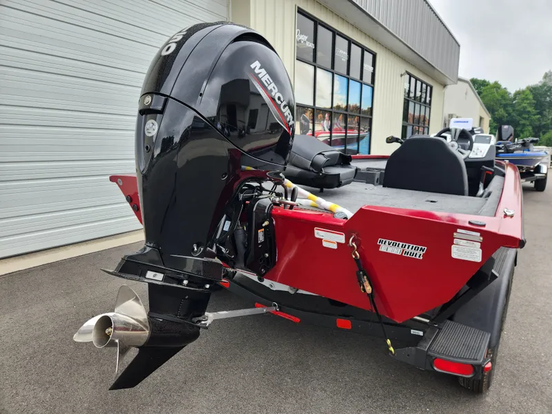 Slide: The Image of 2026 Tracker Pro Team 195 boat with Mercury engine, red hull, parked outside a building. - 3