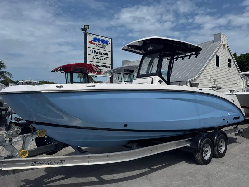 The Image of 2024 Yamaha Boats 255 FSH Sport E in light blue on trailer, dealership background. - 0