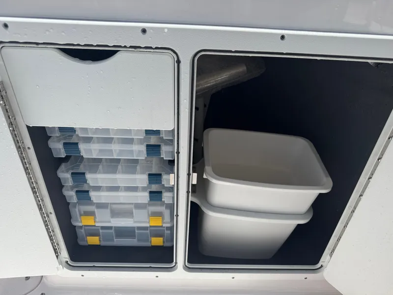 Slide: The Image of Storage compartments on 2024 Yamaha Boats 255 FSH Sport E, featuring tackle boxes and bins. - 18
