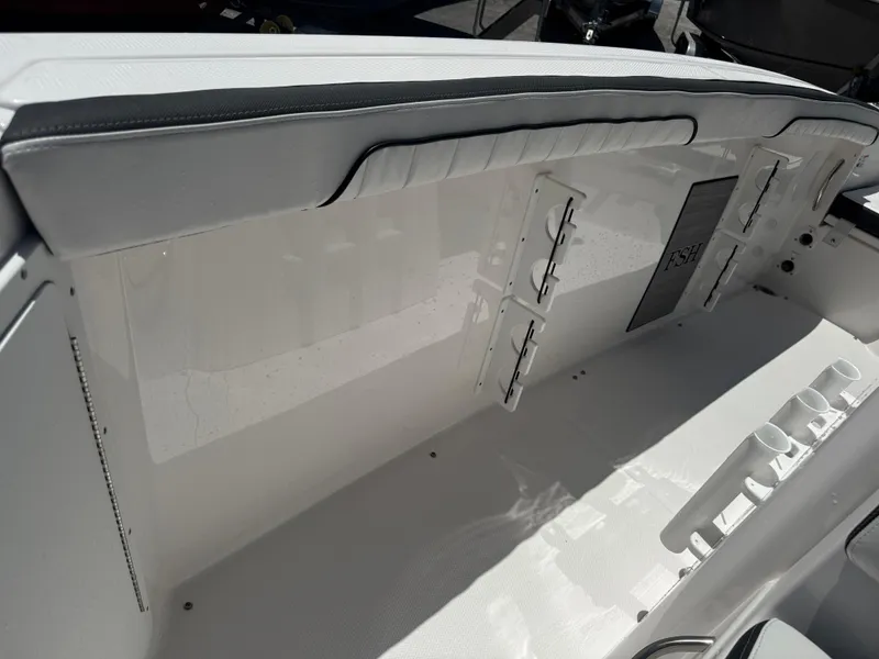 Slide: The Image of 2024 Yamaha Boats 255 FSH Sport E interior with rod holders and cushioned seating. - 20