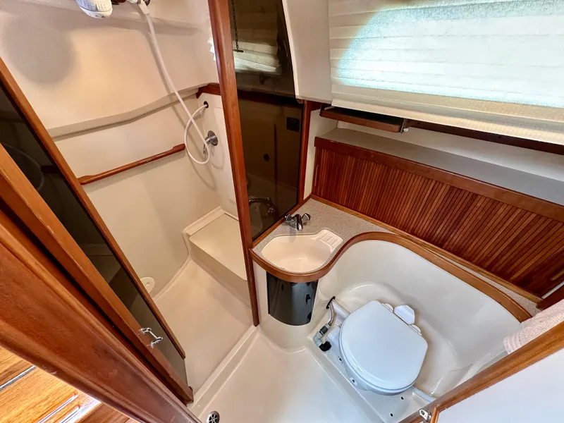 Slide: The Image of 1998 Sabre 362 yacht bathroom with shower, sink, and toilet, featuring wood accents and compact design. - 20