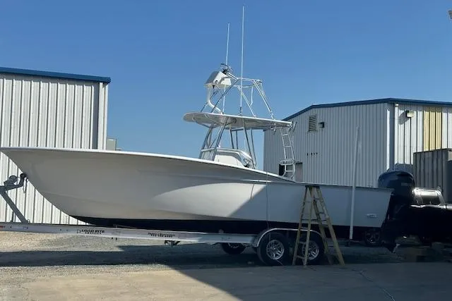 Slide: The Image of 2025 Custom Carolina Forbes boat on water, with person standing on deck, under cloudy sky. - 8