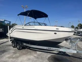 Slide: The Image of 2021 Bayliner DX 2200 boat on trailer with canopy, parked outdoors. - 2