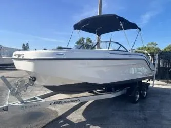 Slide: The Image of 2021 Bayliner DX 2200 boat on trailer with canopy, parked outdoors. - 4